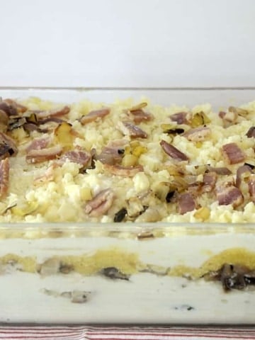 Baking dish of vegetable lasagna showing creamy layers.