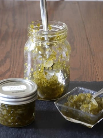 Jar of candied jalapenos with a little saucer of relish-consistency candied jalapenos.